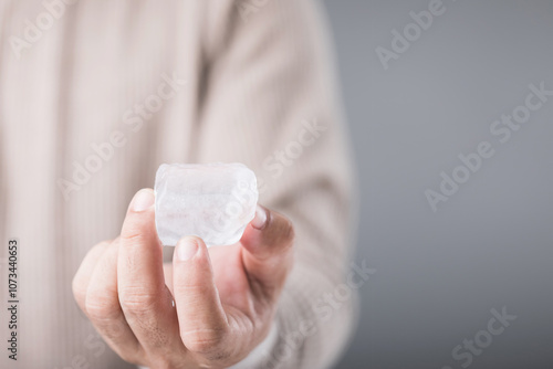Wallpaper Mural Man holding an ice cube, with a look of discomfort due to the cold, highlighting the sensitivity and potential tooth pain from consuming cold foods. Emphasizing oral health and dental care Torontodigital.ca