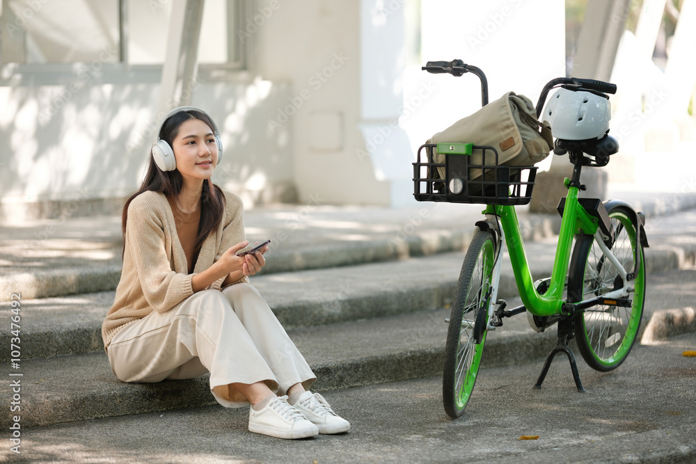 Obraz premium A woman is sitting on a set of stairs with a green bicycle next to her