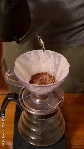 Close-up of brewing filtered coffee, soaking ground coffee with water, vertical video
