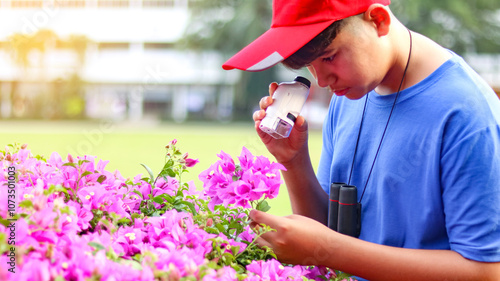 An Asian boy using a microscope to study and explore species of plants in local park.