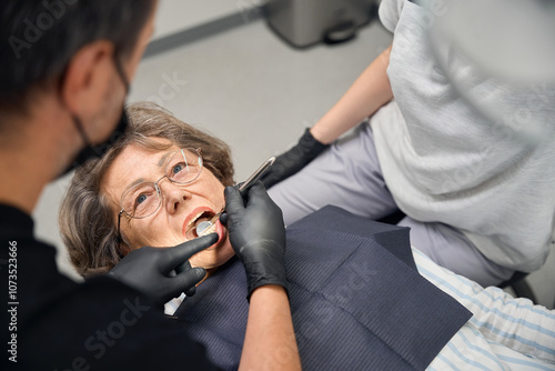 Dentist surgeon examines teeth of elderly lady