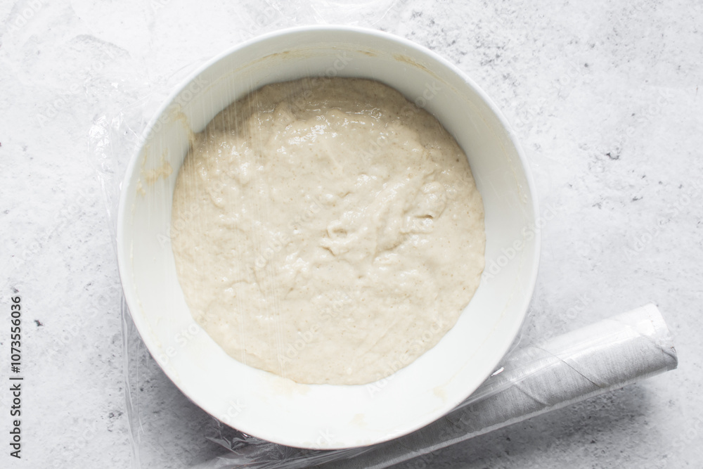 Overhead view of nigerian puff-puff dough that has proofed, puff-puff dough in a white mixing bowl, process of making puff-puff or bofrot Overhead view of nigerian puff-puff dough that has proofed, puff-puff dough in a white mixing bowl, process of making puff-puff or bofrot