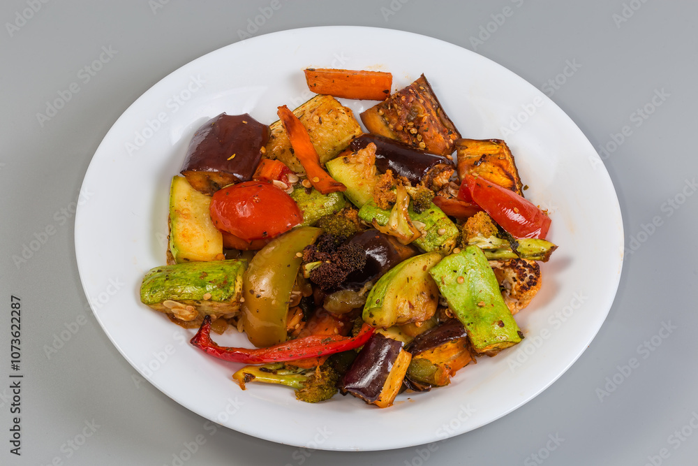 Different baked vegetables on dish on a gray background Different baked vegetables on dish on a gray background