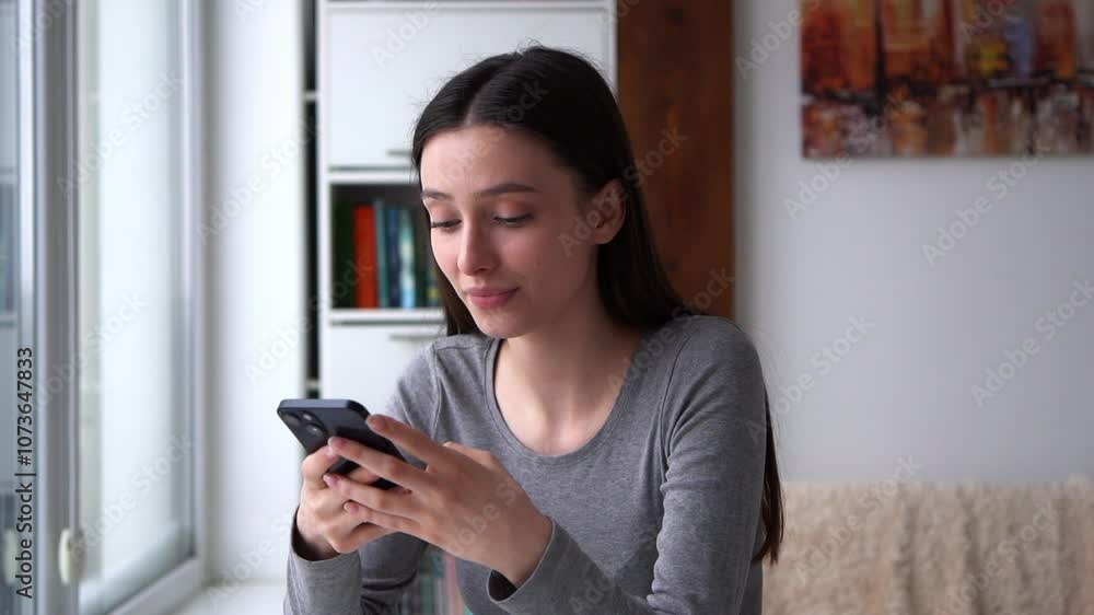 Beautiful woman smiling happily while chatting on smartphoneA beautiful young woman smiles with happiness while chatting on her smartphone indoors. Bright and joyful atmosphere, perfect for concepts Beautiful woman smiling happily while chatting on smartphoneA beautiful young woman smiles with happiness while chatting on her smartphone indoors. Bright and joyful atmosphere, perfect for concepts