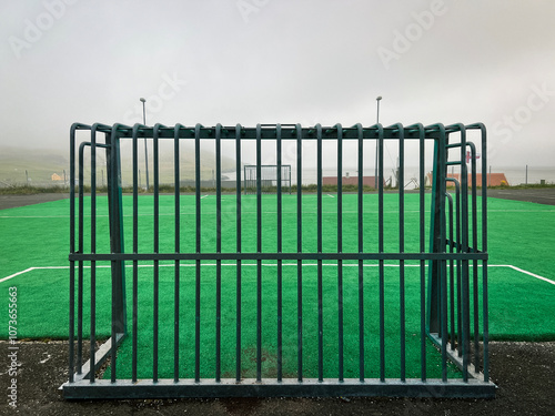 Rear view of a metal soccer goal structure within a soccer or football field. Low clouds hang over the scene with views of the North Atlantic Ocean. Nólsoy, Faroe Islands photo