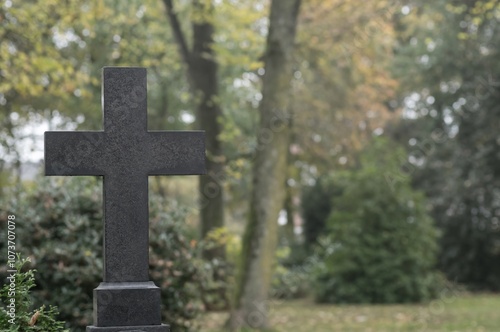 Dark stone cross standing in cemetery representing faith and remembrance