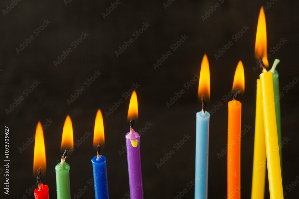 Colored Hanukkah candles burn on the holiday on a black background Colored Hanukkah candles burn on the holiday on a black background