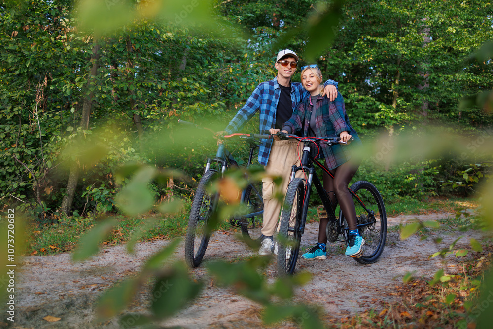 Obraz premium Portrait of happy young man and girl with bicycles in the forest