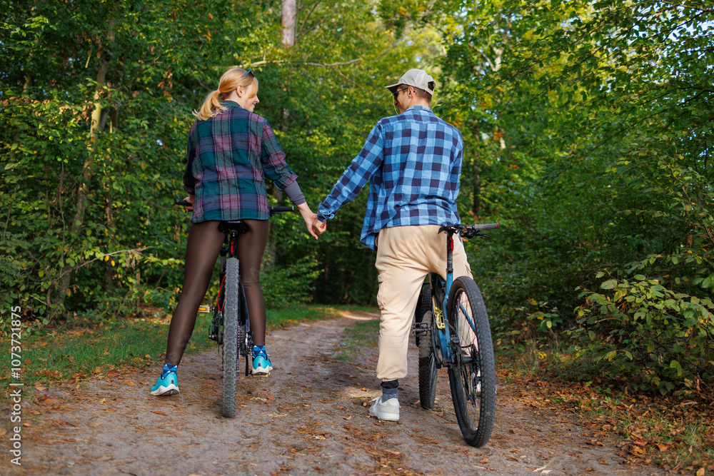 Young couple on bicycles holding hands on a forest road Young couple on bicycles holding hands on a forest road