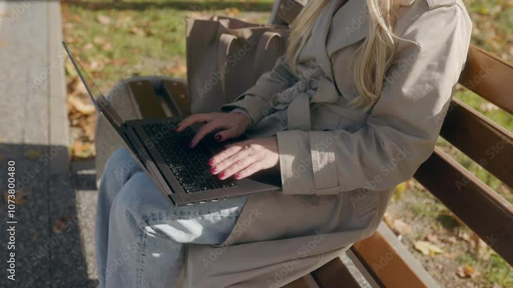 Woman is sitting on a bench with a laptop open in front of her Woman is sitting on a bench with a laptop open in front of her