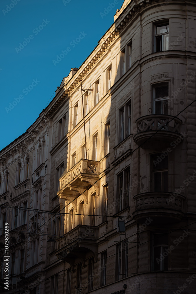 A tall building with balconies casts a shadow on the street below. A tall building with balconies casts a shadow on the street below.