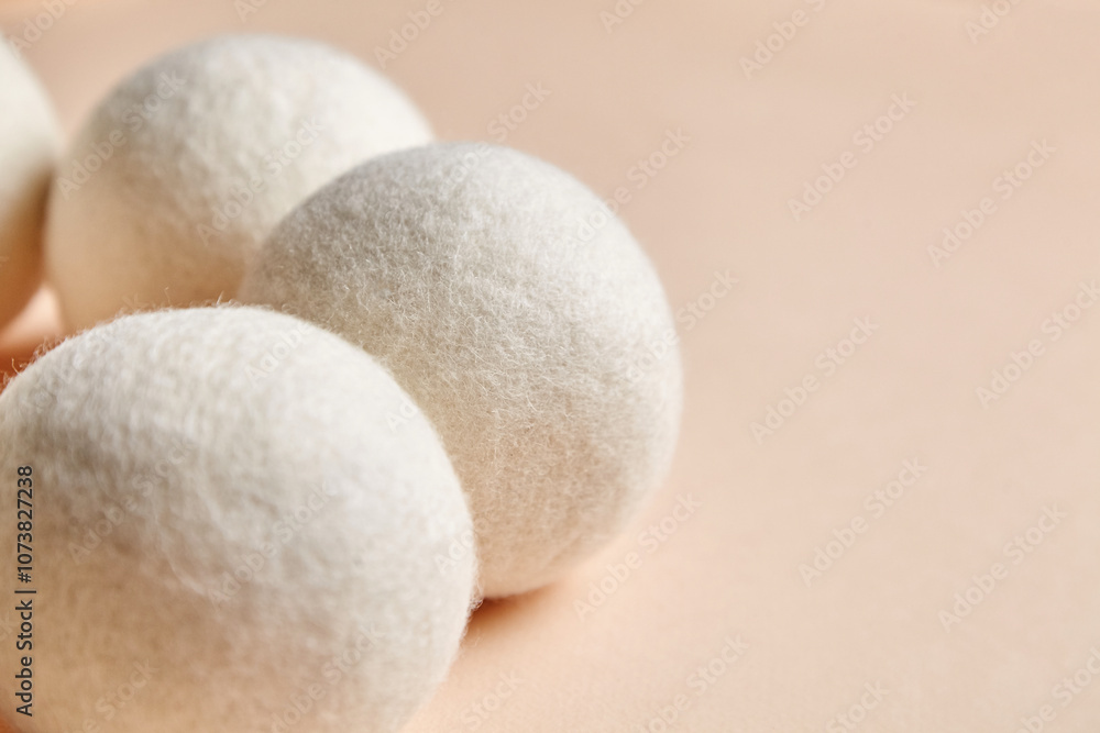 Soft wool dryer balls arranged on a beige surface. Eco-friendly, reusable solution for reducing static and wrinkles in laundry, made from natural wool. Soft wool dryer balls arranged on a beige surface. Eco-friendly, reusable solution for reducing static and wrinkles in laundry, made from natural wool.