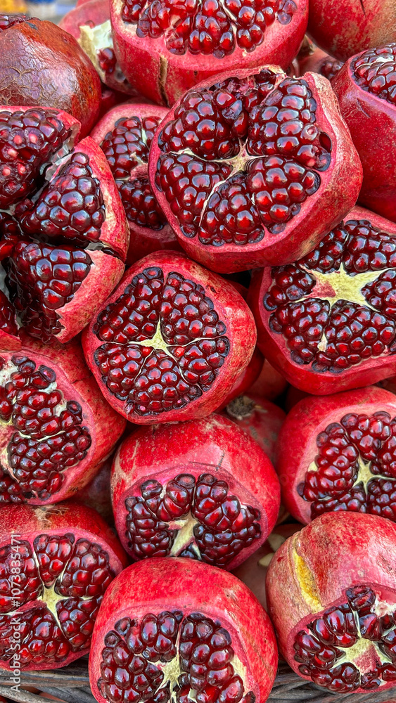Freshly cut pomegranates display their vibrant red seeds, ideal for culinary and health themes, photographed at a market setting, appealing to food industries and nutrition-focused content Freshly cut pomegranates display their vibrant red seeds, ideal for culinary and health themes, photographed at a market setting, appealing to food industries and nutrition-focused content
