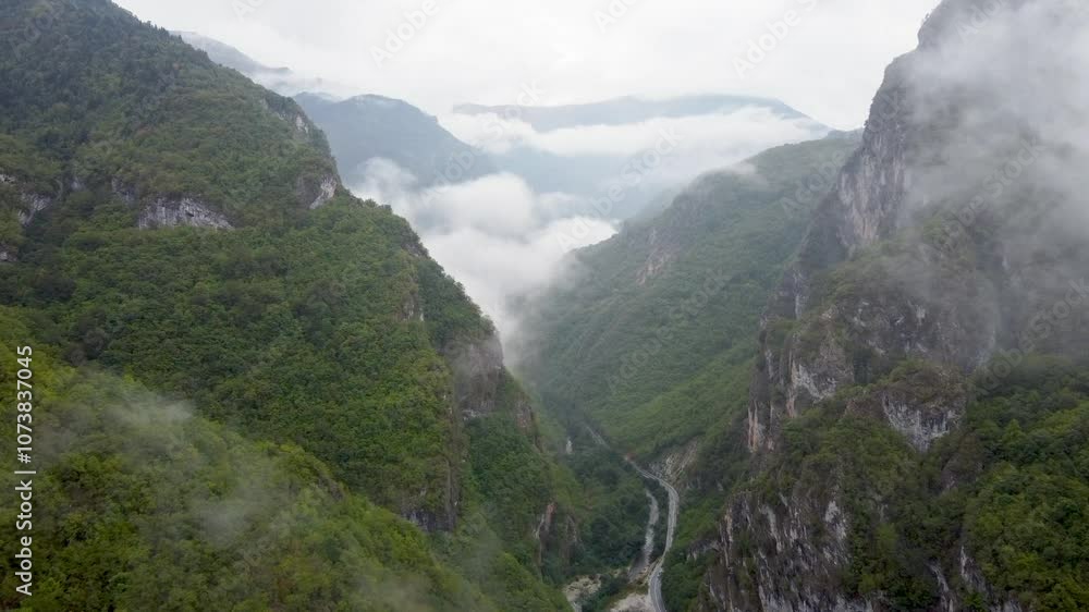 A deep river canyon in the mountain, aerial drone view. Green trees on mountain in autumn. Fog in gorge. A deep river canyon in the mountain, aerial drone view. Green trees on mountain in autumn. Fog in gorge.