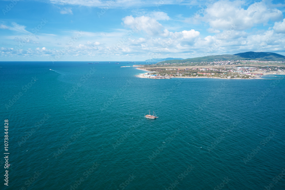 Panoramic view of the azure sea surface with a floating ship. A lot of tankers and dry cargo ships at anchor waiting for unloading and loading. Shooting from a drone. Panoramic view of the azure sea surface with a floating ship. A lot of tankers and dry cargo ships at anchor waiting for unloading and loading. Shooting from a drone.
