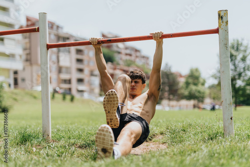 Fit man exercising on a pull-up bar in an outdoor park, demonstrating strength and endurance on a sunny day