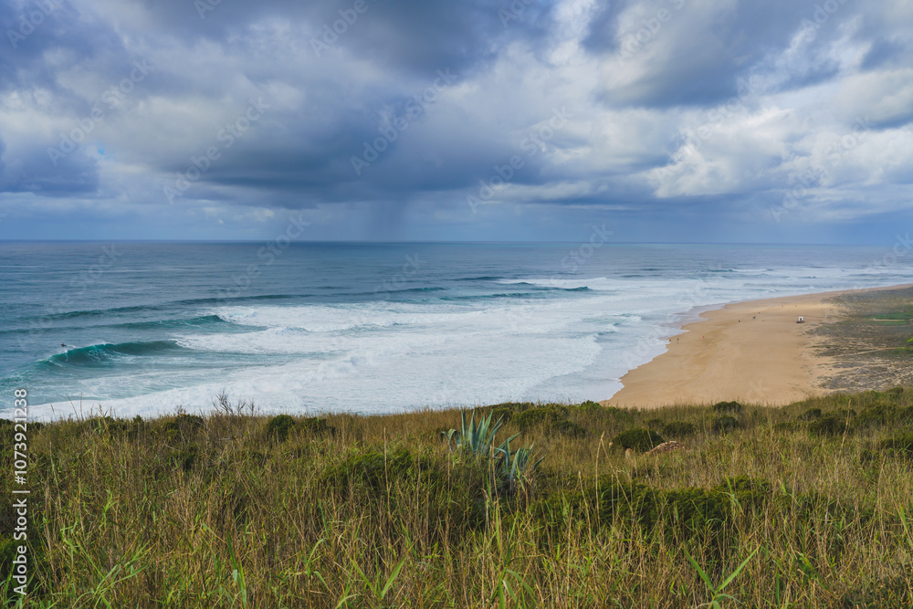 Impending storm casting a dramatic light over the serene and wild Nazare beach. Impending storm casting a dramatic light over the serene and wild Nazare beach.