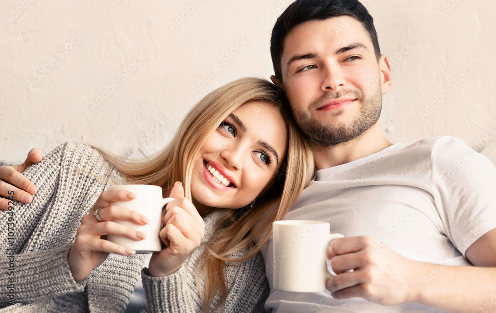 Millennial guy and his girlfriend with hot drinks spending time together at home, panorama Millennial guy and his girlfriend with hot drinks spending time together at home, panorama