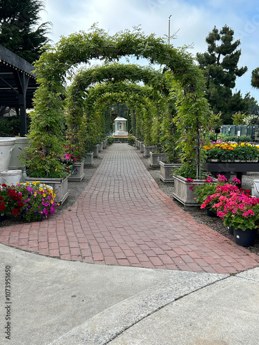 A picturesque brick-paved pathway bordered by lush flower beds in full bloom, with vibrant, colorful flowers flanking both sides.