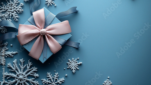 Gift box with pink and blue ribbons surrounded by frosted snowflakes on a light blue background