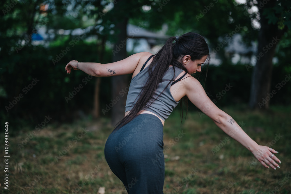 A woman in athletic wear gracefully practices her balance in a natural outdoor setting, surrounded by lush greenery. The scene captures a moment of relaxation and focus. A woman in athletic wear gracefully practices her balance in a natural outdoor setting, surrounded by lush greenery. The scene captures a moment of relaxation and focus.