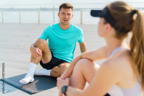 A Man and Woman Converse While Exercising Outdoors on a Sunny Day at a Waterfront Location