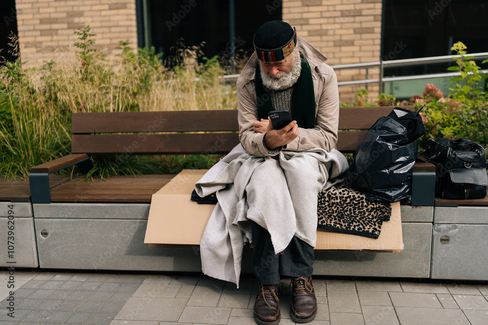 Obraz premium Portrait of mature adult man sitting on city bench, using typing smartphone amidst urban solitude, shedding light on poverty and isolation in aging populations. Concept of poor unhappy retirement.
