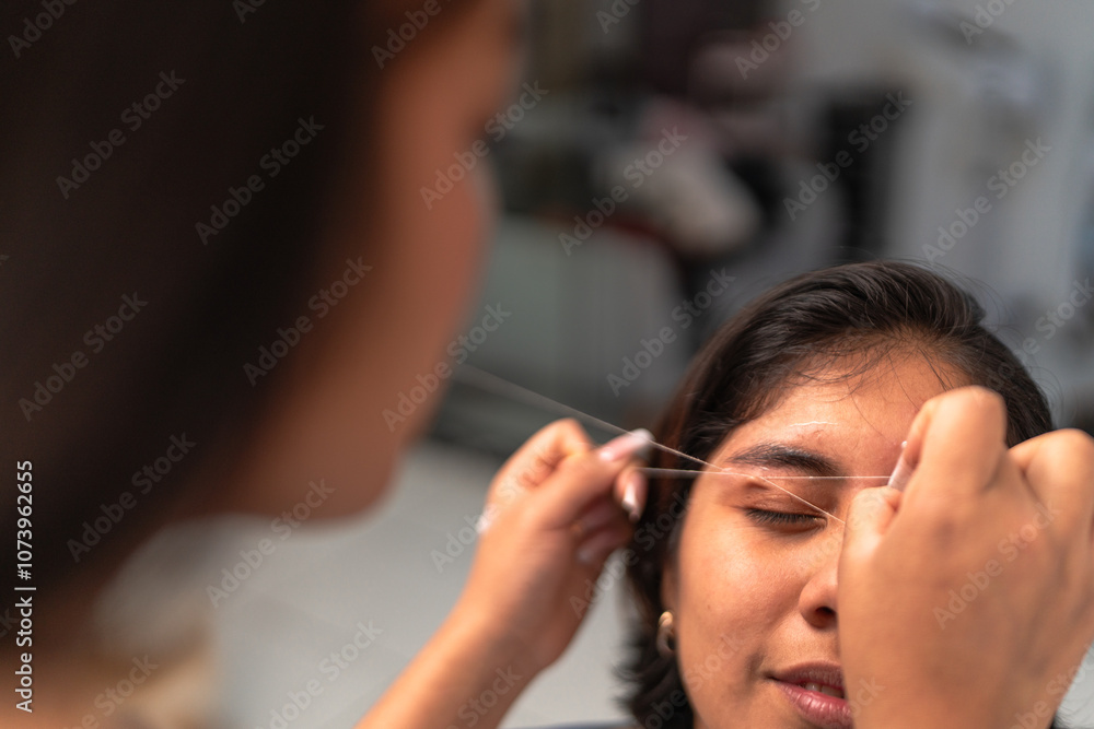 Fototapeta premium Beautician shaping eyebrows with thread close up