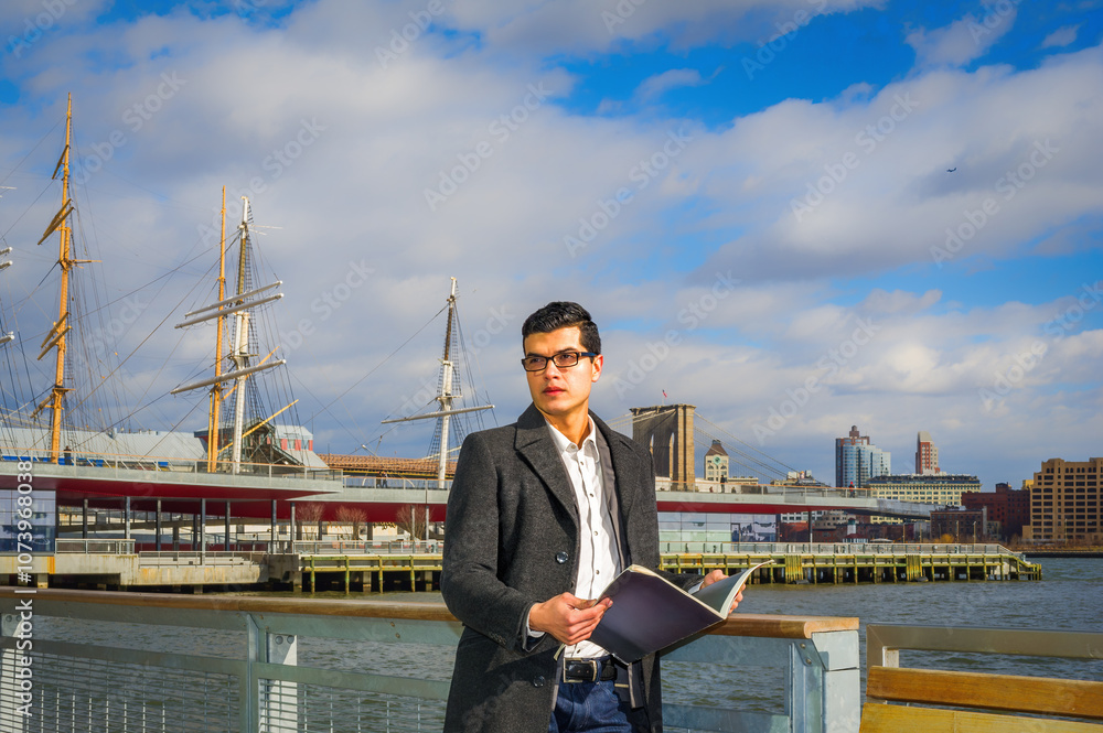 A man dressed in a coat stands by the waterfront, holding an open book. Behind him, several tall ships and a city skyline are visible under a partly cloudy sky.