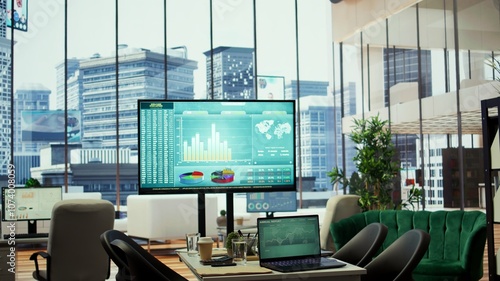 In a professional boardroom, computer screen showcases business data and statistics, aiding executives in strategy planning. Empty office space for meeting to help with workflow optimization.