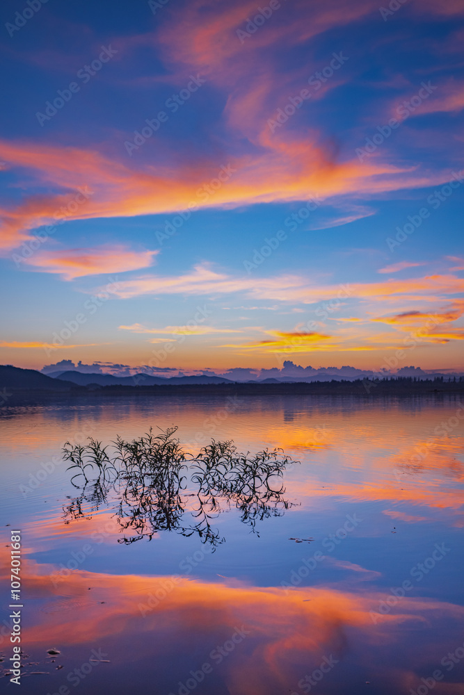 Fototapeta premium Landscape of mountains and lake at sunset and clouds reflected in the water.