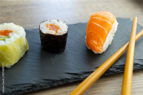 close-up photo of a sushi plate with Salmon avocado eel nigiri maki and wooden chopsticks on a gourmet restaurant table. photo