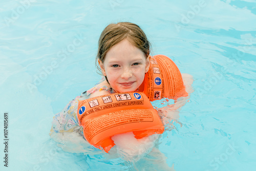 Tableau sur toile Happy girl are swimming in a pool wearing orange armbands.