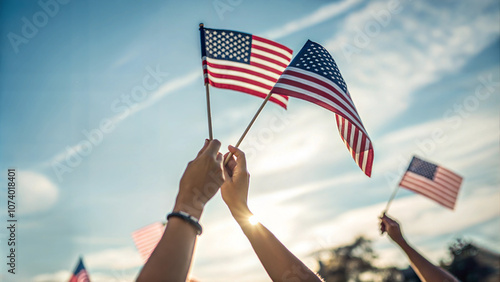 Hands holding small American flags against a bright blue sky, symbolic unity