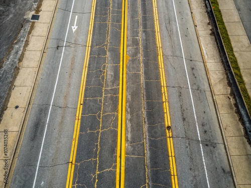 Aerial View of Yellow Double Lines on Tarmac Road with Weathered Paint Texture, Featuring Urban Driveway and Highway Traffic Markings in a Straight Pattern photo