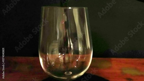 Pouring red wine into a glass. Pouring wine on a dark background. Super slow motion. Concept of gastronomy and culinary