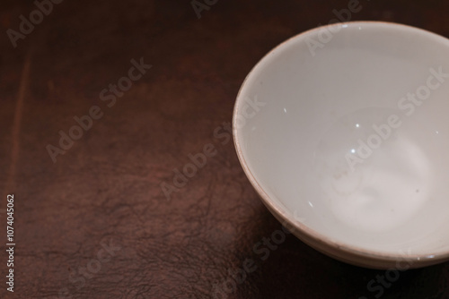 Overhead view of a mini white ceramic bowl on a brown background, Top view of a white ceramic mixing bowl, Flat lay of ceramic batter bowl