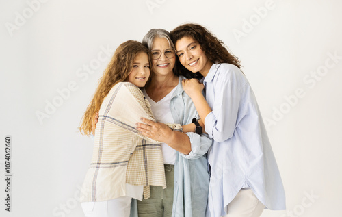 Quadro su tela Happy caucasian senior, mature and teen women hugging, enjoy love on white wall background