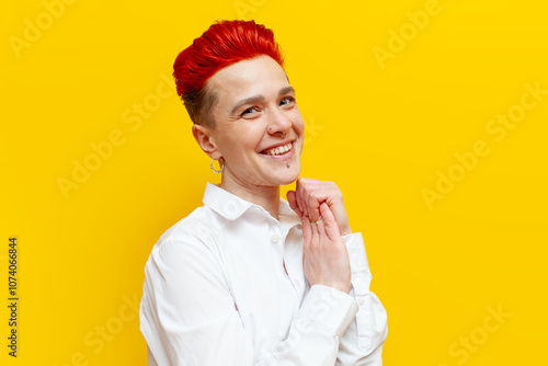 Fotografie young short-haired red-haired grateful girl is touched and shy on a yellow isola