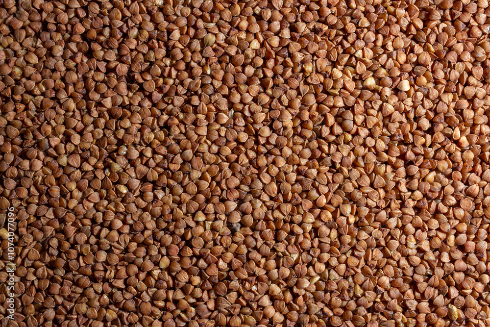 Dry Uncooked Brown Buckwheat Groats Background - Top View, Flat Lay. Raw Large Buckwheat Grains. Russian, Ukrainian and Belarusian Culture Dry Uncooked Brown Buckwheat Groats Background - Top View, Flat Lay. Raw Large Buckwheat Grains. Russian, Ukrainian and Belarusian Culture