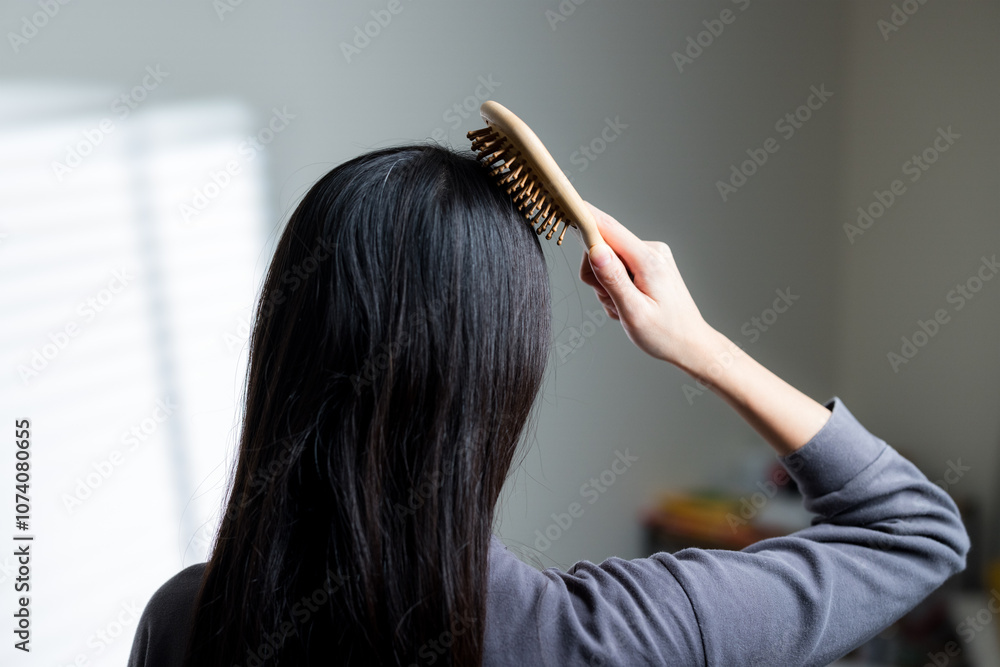 Naklejka premium Woman Brushing Long Black Hair at Home
