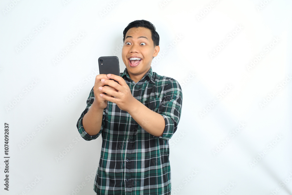 asian man surprised looking at smartphone isolated on white background, wearing casual green shirt asian man surprised looking at smartphone isolated on white background, wearing casual green shirt