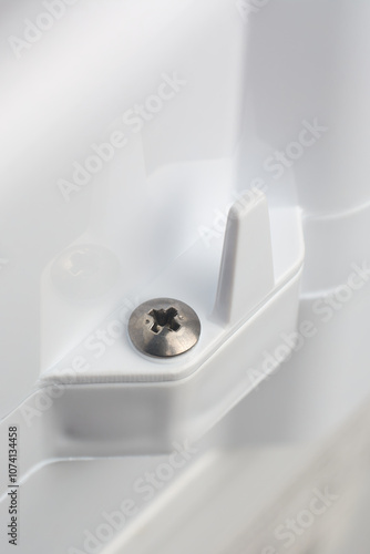 close-up of phillips crosshead screw head mounted on white textured plastic product or appliance surface, soft focus with copy space photo