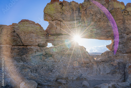 Spectacular sunburst piercing through natural rock formation with multicolored lichen patterns. Famous Window of Sunset viewpoint at Isalo National Park, Madagascar. photo