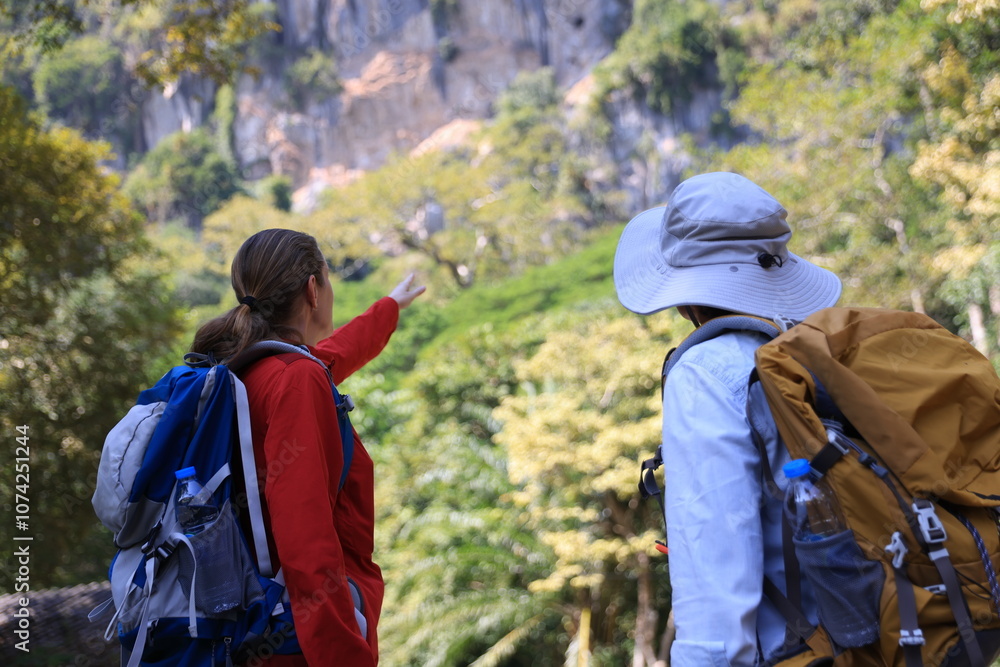 Two Senior women hiking and walking in the autumn forest and exploring the rock cave in the middle of the jungle Two Senior women hiking and walking in the autumn forest and exploring the rock cave in the middle of the jungle