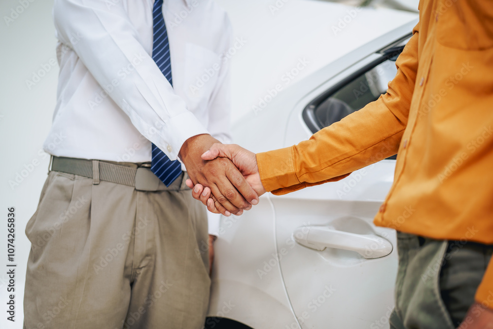 Fototapeta premium Asian clients engage with a car insurance agent beside a wrecked vehicle. They examine the policy details, assess the damage, and finalize paperwork related to the insurance claim and repairs.
