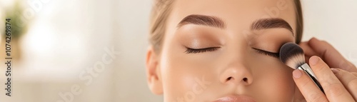 Close-up of a woman applying makeup with a brush carefully.