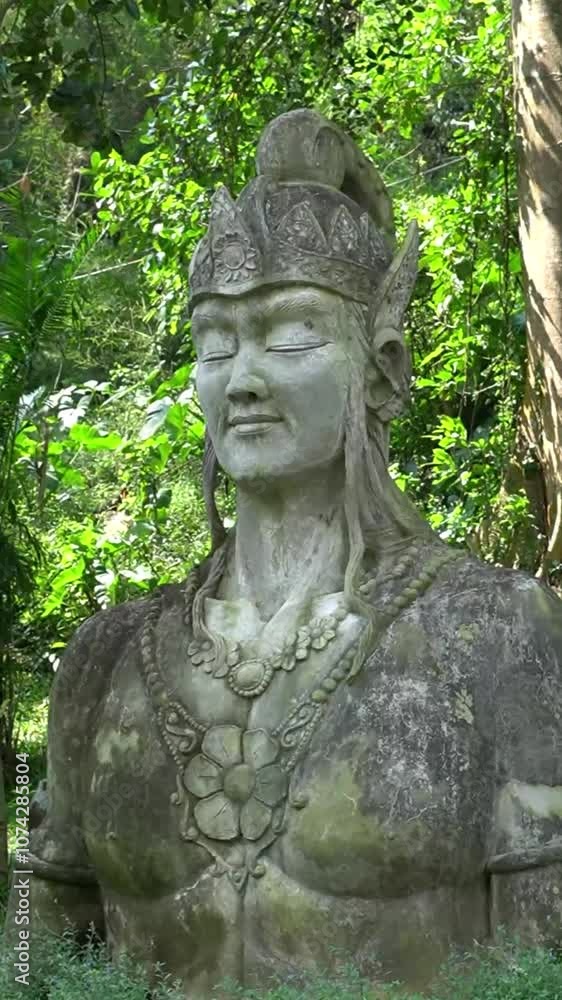 Giant statue of a god or goddess from an Indonesian story with a background of green trees in cinematic Giant statue of a god or goddess from an Indonesian story with a background of green trees in cinematic