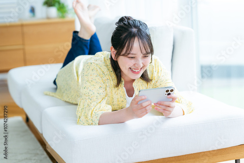 部屋でスマホを操作する若い女性 photo