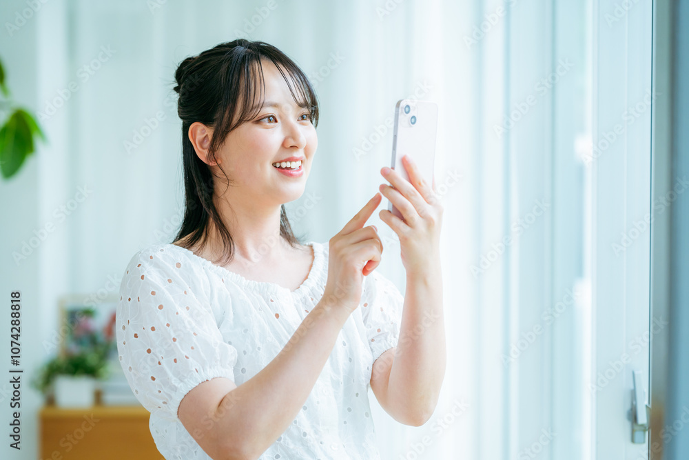 部屋でスマホを操作する若い女性